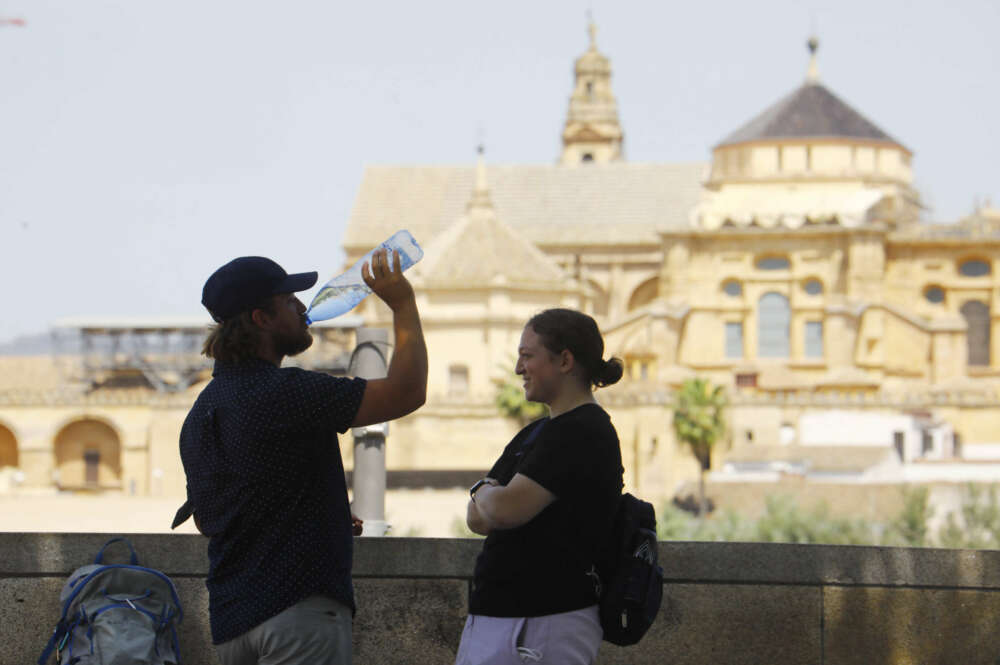 CÓRDOBA, 18/05/2022.- Dos turistas descansan y beben agua frente a la Mezquita -Catedral de Córdoba, hoy miércoles cuando se han alcanzado los 38 grados en la capital y la Aemet prevé ascenso de temperatura en Andalucía. EFE/Salas