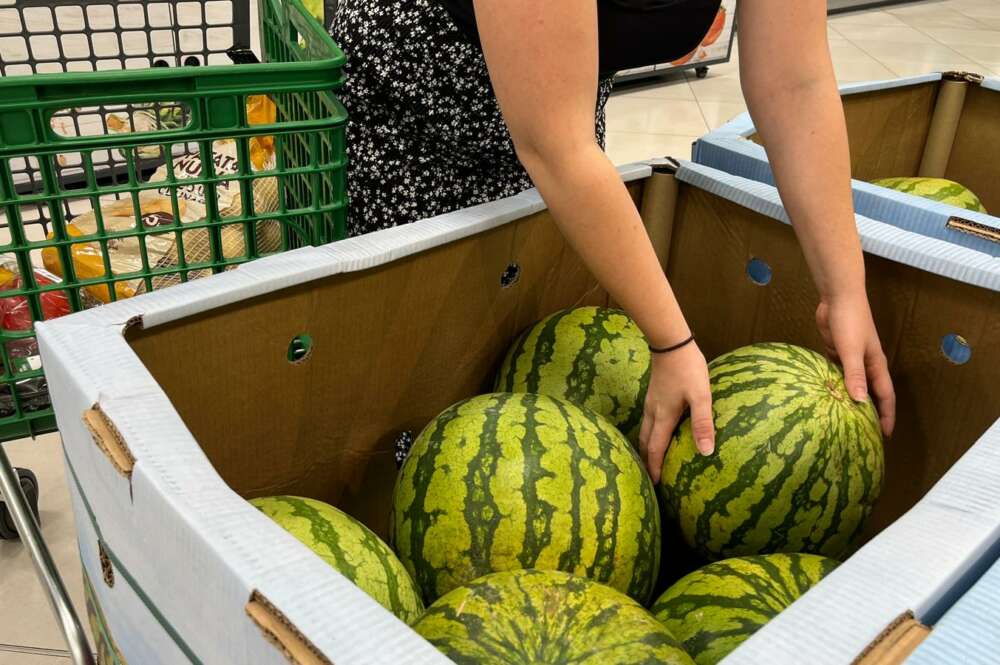 Una persona coge una sandía en un supermercado.