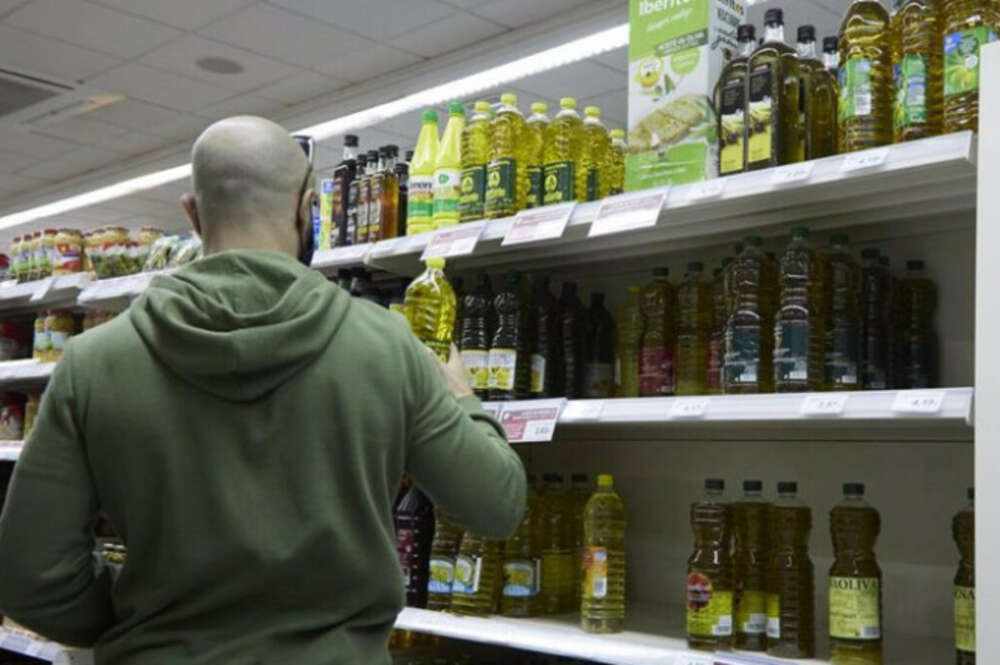 Una persona compra aceite en un supermercado.