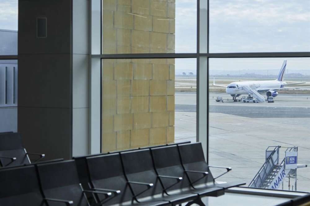 Detalle de una terminal del Aeropuerto de Sevilla con un avión estacionado en mitad de la pista.