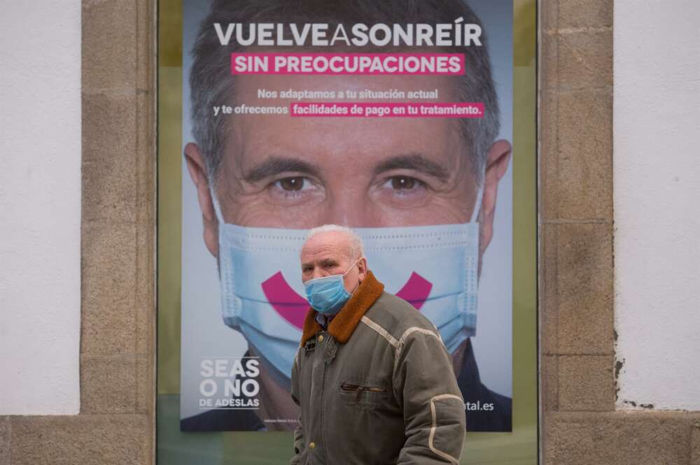 Un hombre con mascarilla pasa frente a un cartel publicitario en Lugo, tras el levantamiento del cierre perimetral de la ciudad, en Lugo, Galicia (España), a 30 de diciembre de 2020. Lugo y Ourense serán las dos únicas urbes gallegas sin cierre - Carlos Castro