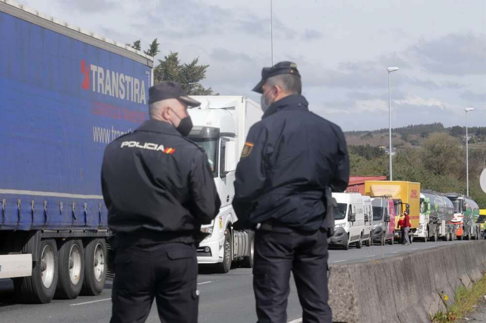 Dos agentes de Policía Nacional observan los camiones parados en el arcén en uno de los accesos al Polígono de O Ceao. Foto: Europa Press