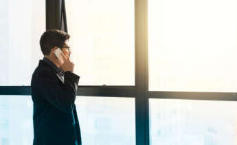 empresario mirando por la ventana mientras llama por teléfono