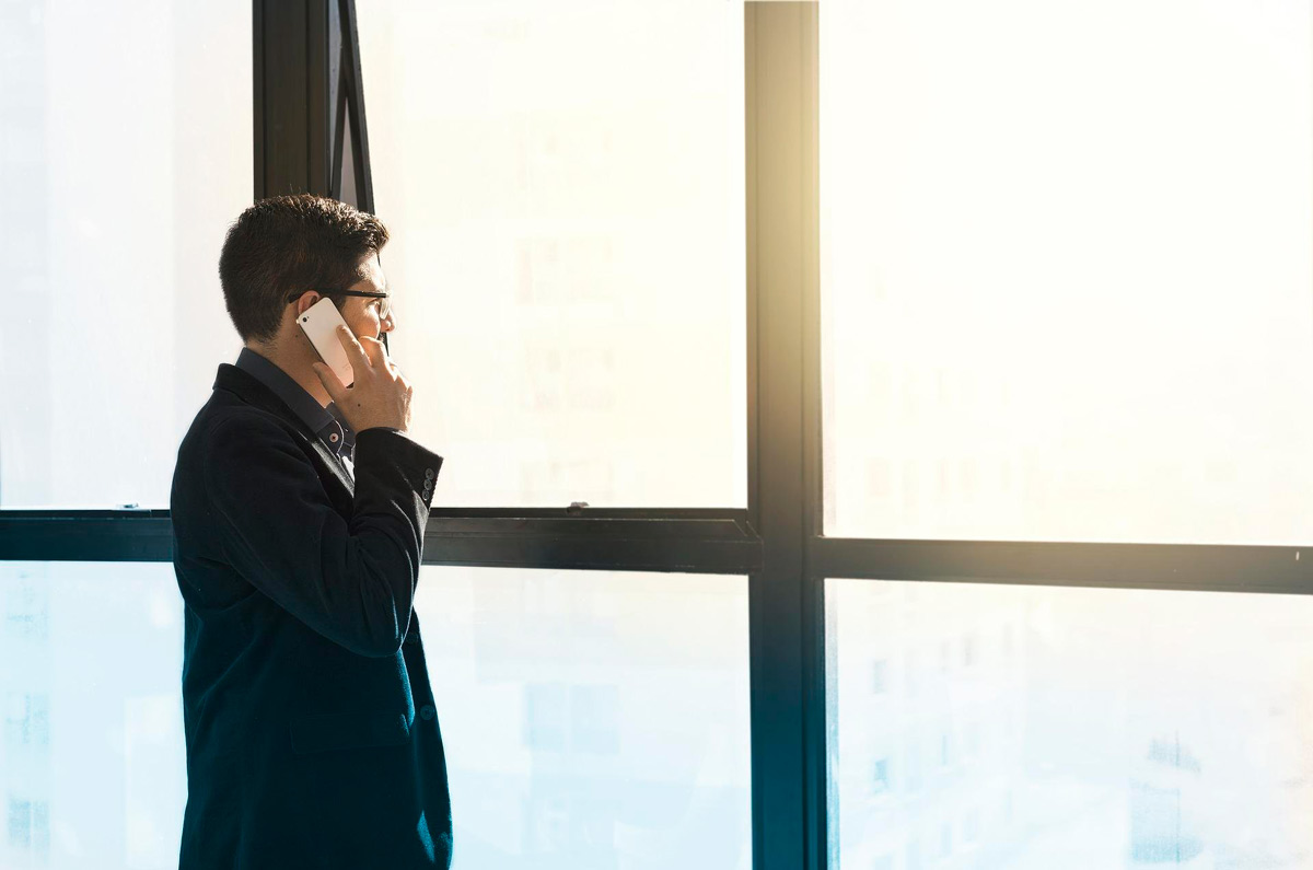 empresario mirando por la ventana mientras llama por teléfono