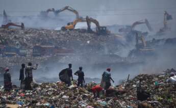 Los denominados 'rebuscadores' de la basura observan cómo el humo sale del vertedero de Perungudi después de que eun gran incendio un par de días antes, en Chennai, India, el 29 de abril de 2022