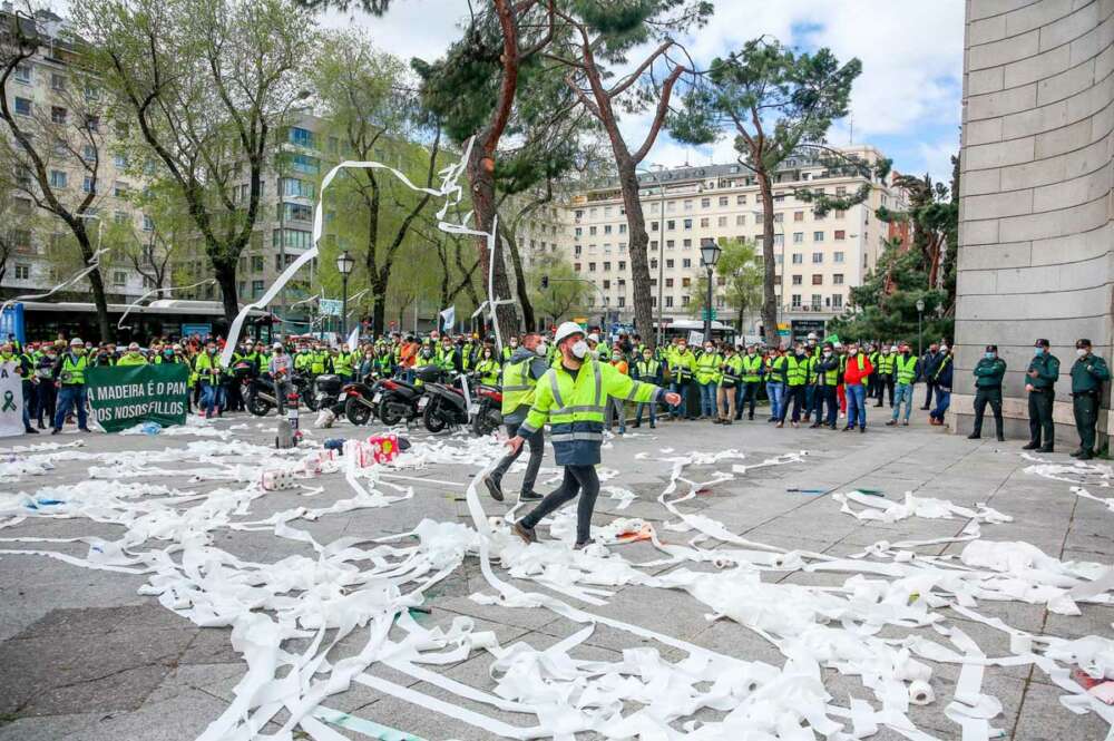 Trabajadores de la factoría pontevedresa de ENCE se concentran con chalecos amarillos, humo, pancartas y tirando rollos de papel higiénico en las inmediaciones del Ministerio de Transición Ecológica en Madrid