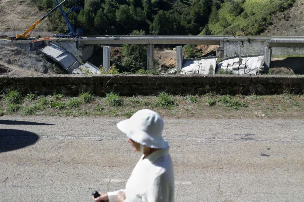 Una mujer camina por la carretera mientras se realiza el desmontaje de las pilas 1 y 2 del viaducto de O Castro, en el kilómetro 430 sentido A Coruña de la autovía A-6. - Carlos Castro -