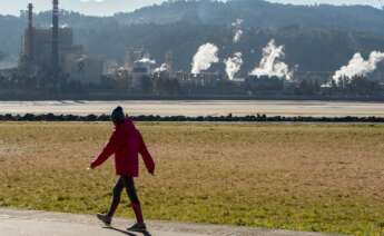 Una mujer pasea junto a la fábrica de Ence en Pontevedra