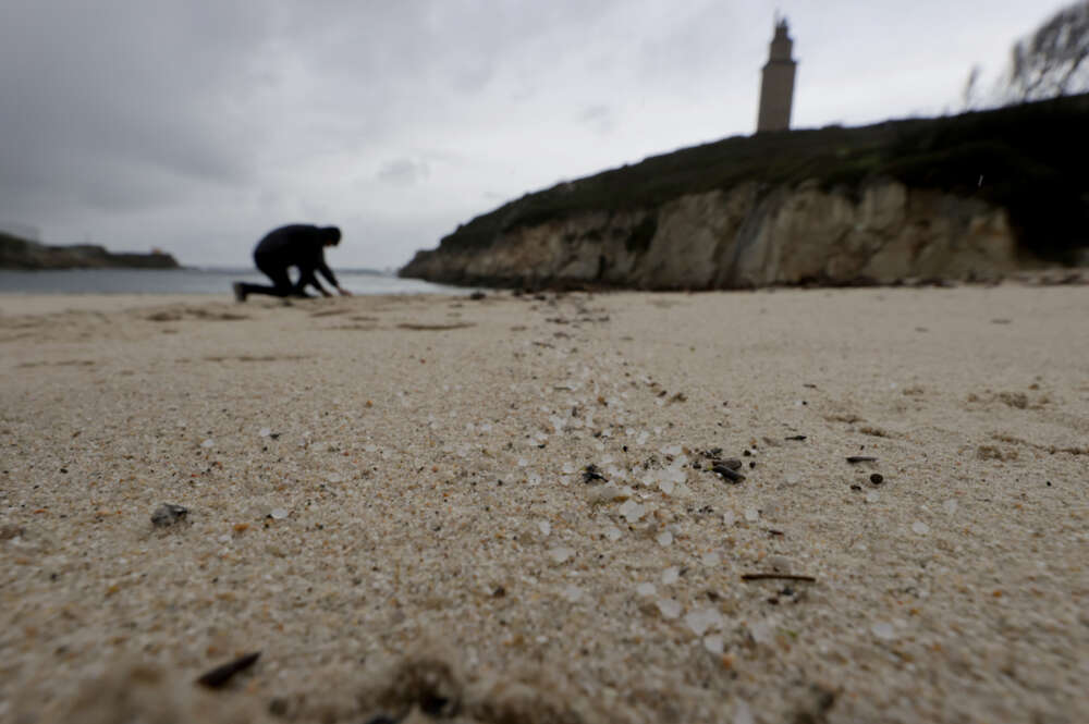 Una persona recoge pellets en la playa de As Lapas, situada a los pies de la Torre de Hércules, en una jornada en la que continúa la llegada a los arenales gallegos de las pequeñas esferas de plástico tras la caída de un contenedor del buque Toconao el pasado mes de diciembre.- EFE/Cabalar