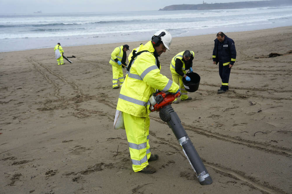 Operarios con aspiradores esta mañana en la playa asturiana de Salinas. El Principado ha identificado 65 de los 210 arenales asturianos como prioritarios para los trabajos de vigilancia y retirada de los 'pellets' microplásticos llegados a la costa, en los que este miércoles participan unas 170 personas. EFE/Paco Paredes