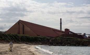 Una persona camina por una playa cercana a la factoría de Alcoa, en San Cibrao (Lugo) / EFE / Emilio Pérez