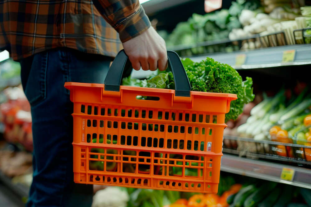 Persona con una cesta naranja comprando en un supermercado