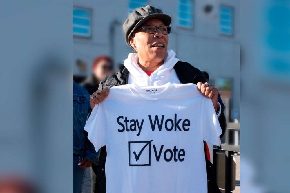 La excongresista de los Estados Unidos, Marcia Fudge, sosteniendo una camiseta con la frase "Stay Woke: Vote" en 2018