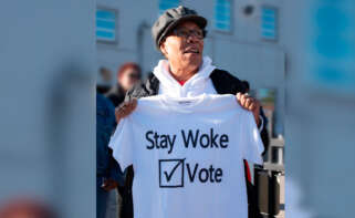 La excongresista de los Estados Unidos, Marcia Fudge, sosteniendo una camiseta con la frase "Stay Woke: Vote" en 2018