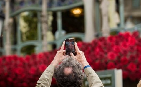 Un turista toma una foto de la Casa Batlló, llena de flores por Sant Jordi