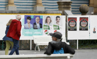 GRAFCAV8279. SAN SEBASTIÁN (ESPAÑA), 16/05/2023.- Unos ciudadanos observan varios carteles electorales este martes en San Sebastián, tras conocerse el comunicado de los siete condenados por asesinatos de ETA que iban en las listas de EH Bildu a las elecciones del próximo 28 de mayo, renunciado a ocupar sus cargos en caso de ser elegidos.- EFE/Juan Herrero.