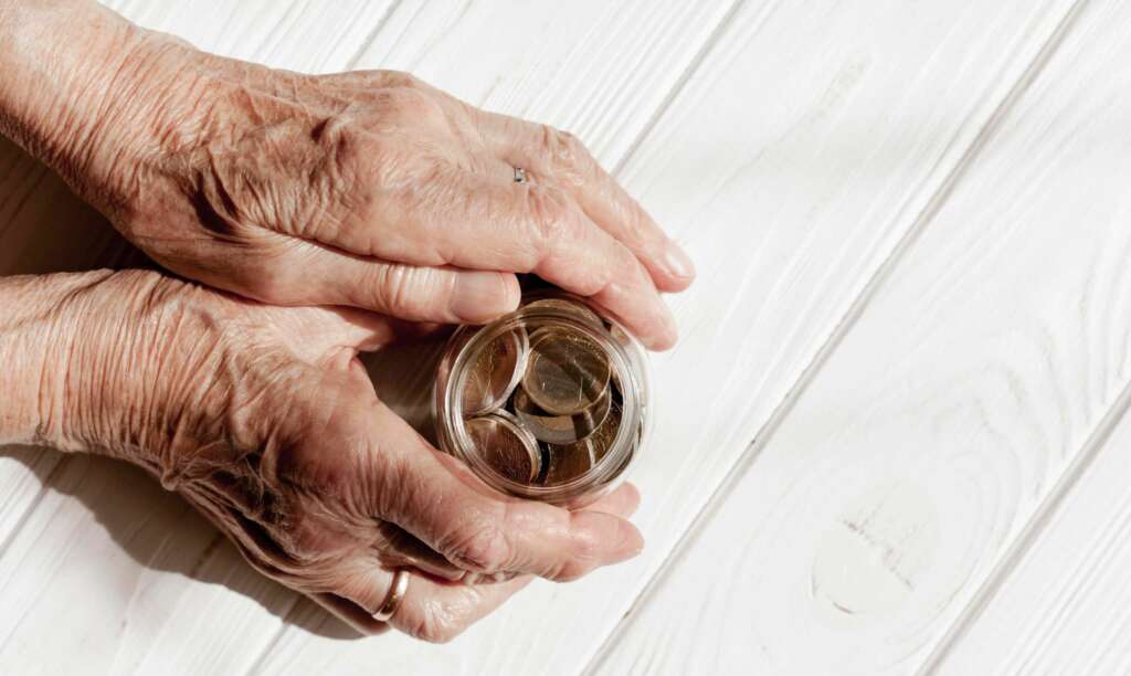 Una anciana coge un frasco con monedas. Foto: Freepik.