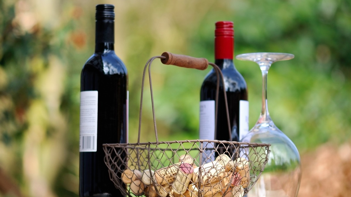 Unas botellas de vino junto con una cesta con corchos