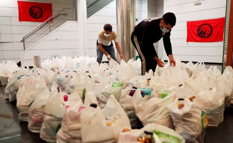 Dos integrantes de la plataforma integrada por organizaciones sociales "Esperanza Obrera" preparan las bolsas de comida en el edificio ocupado la semana pasada en el centro financiero de la ciudad, para el reparto de alimentos llevado a cabo este lunes. EFE/Kai Försterling