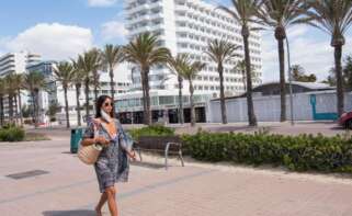 Señora paseando al lado de un complejo de hoteles en la playa.