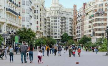 Gente que está paseando por la plaza del Ayuntamiento de Valencia.