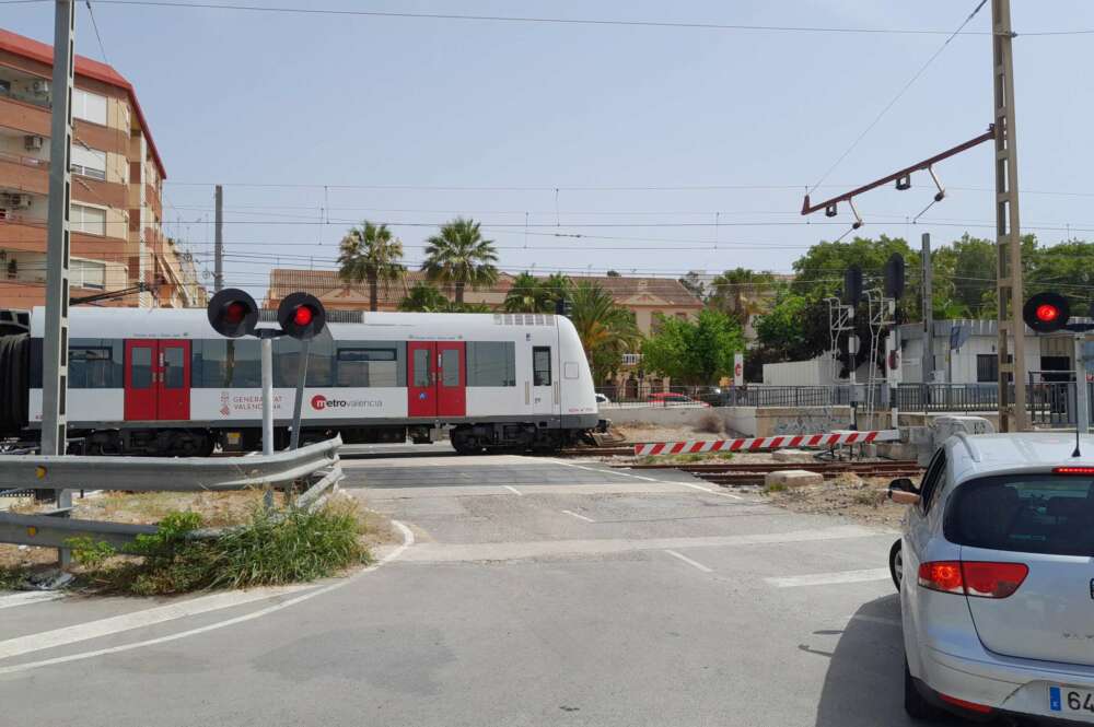 Un cruce de vías en la que aparece un coche y un metro de Metrovalencia en la localidad de Paterna (Valencia)