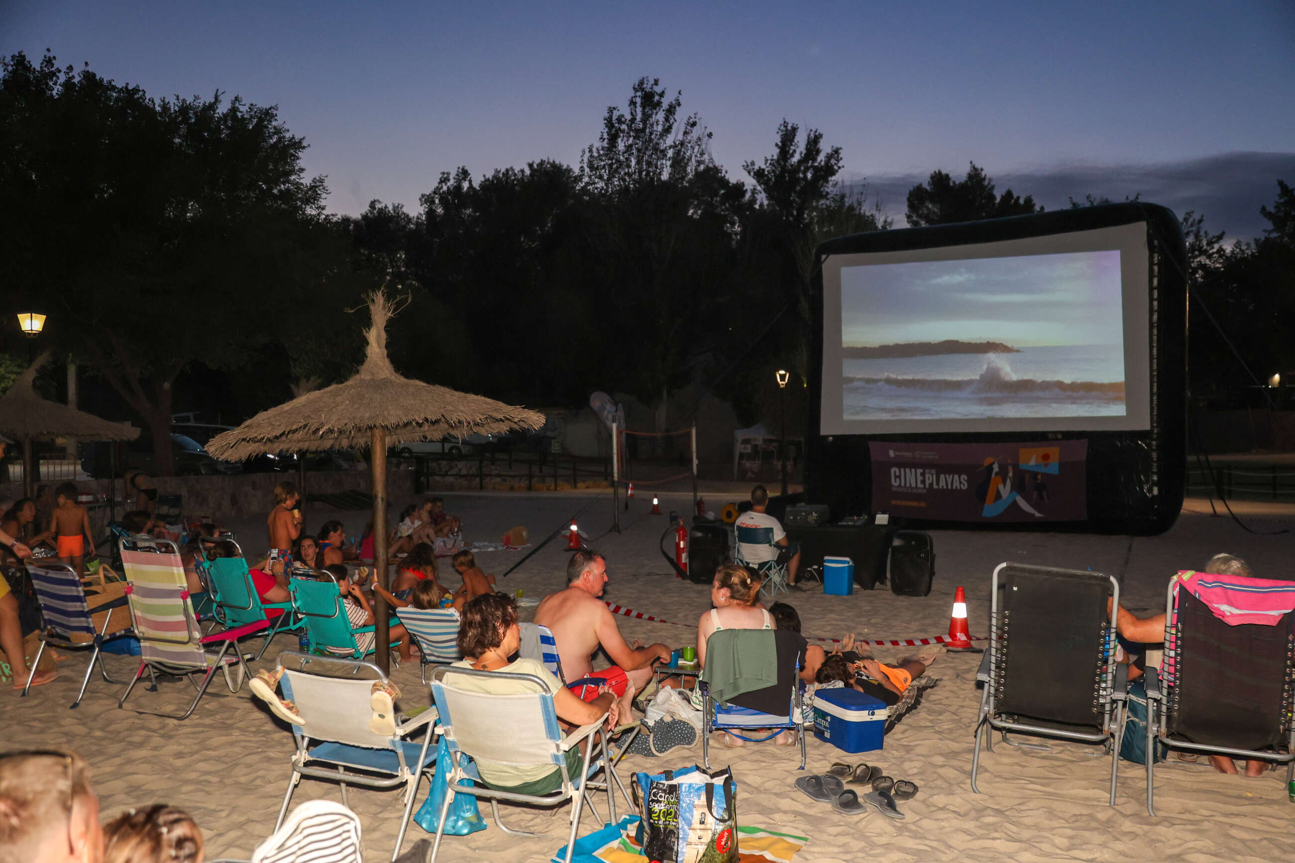 Persones assegudes mirant una pel·lícula en la platja del Navarrés