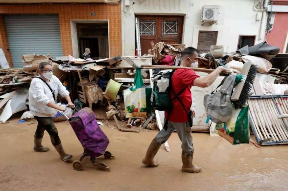 Persones caminant per un carrer de Paiporta arrasat per la DANA