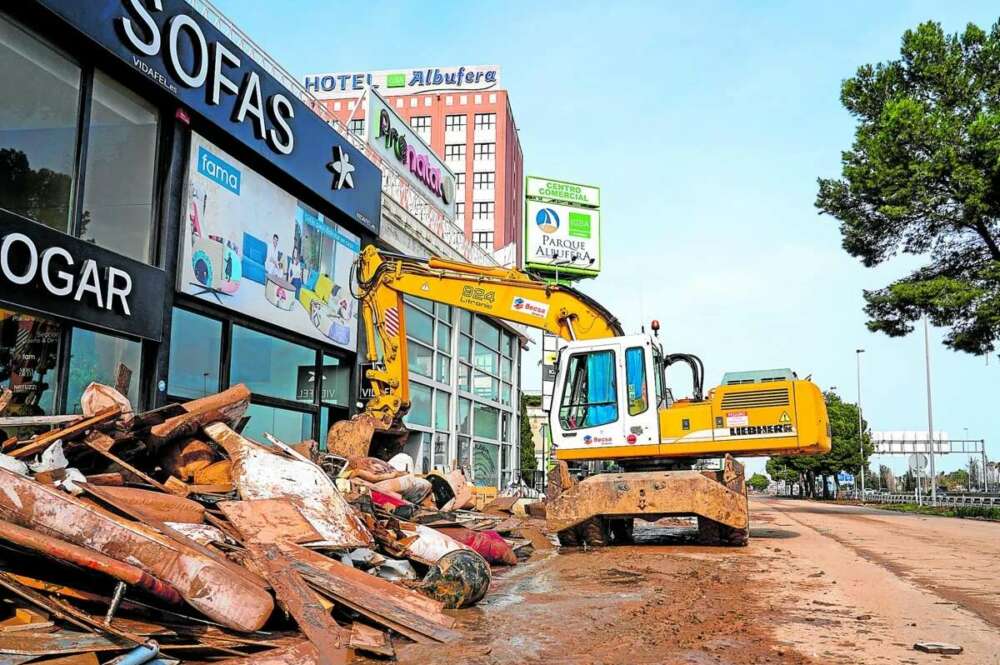 Una grau recogiendo escombros de una empresa afectada por la DANA en Valencia