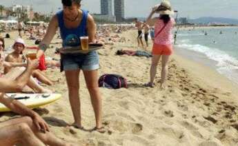 Una camarera sirve una cerveza en la playa. EFE