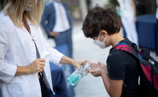 Un niño se desinfecta las manos después de que le tomen la temperatura a la entrada de un colegio de Barcelona. /EFE/Marta Pérez