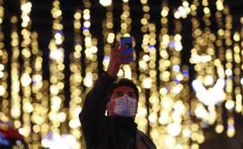 Un transeúnte se fotografía con las luces de Navidad del centro de Barcelona. (EFE)