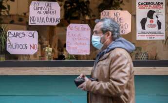 na persona pasa frente a un local de restauración con carteles de protesta por el cierre de la hostelería debido a las nuevas restricciones. EFE / Biel Aliño