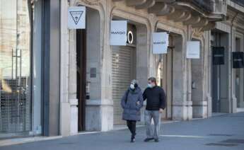 Una pareja pasa por delante de varias tiendas de ropa cerradas este sábado en Barcelona. La tercera ola de la epidemia de COVID sigue aumentando en Cataluña, donde en la última semana se han diagnosticado 24.716 nuevos contagios, 4.527 de ellos ayer, y 408 fallecidos, de los que 64 han sido notificados en las últimas 24 horas. EFE/Marta Pérez