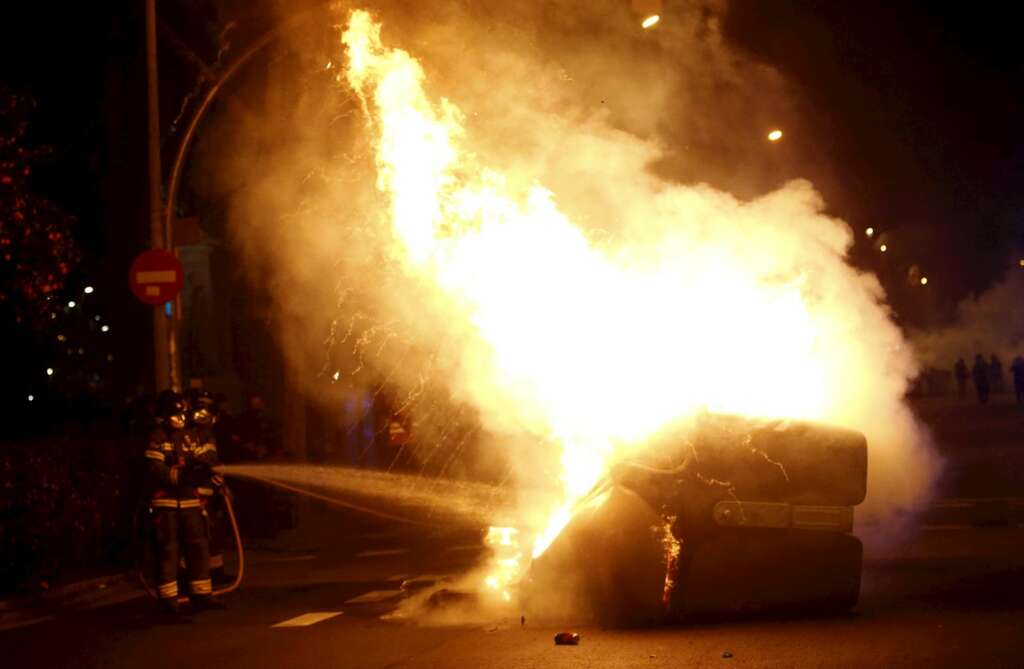 Un bombero apaga un contenedor en llamas durante la manifestación de este viernes, en Barcelona. EFE/Quique García