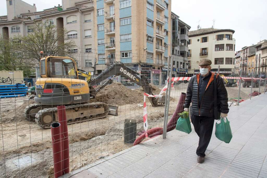 Un vecino pasaba junto a una obra parada en el Coso Bajo de Huesca por las restricciones del primer estado de alarma, en marzo. EFE/ Javier Blasco