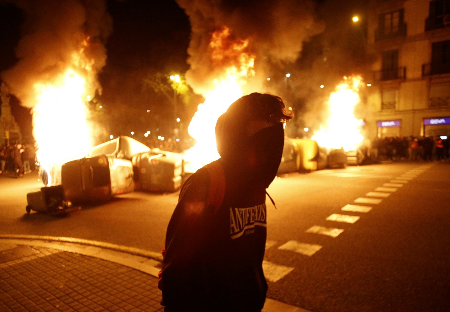 Un manifestante con contenedores ardiendo detrás en la cuarta noche de protestas por la detención del rapero Pablo Hasél, el 19 de febrero de 2021 en Barcelona | EFE/QG/Archivo