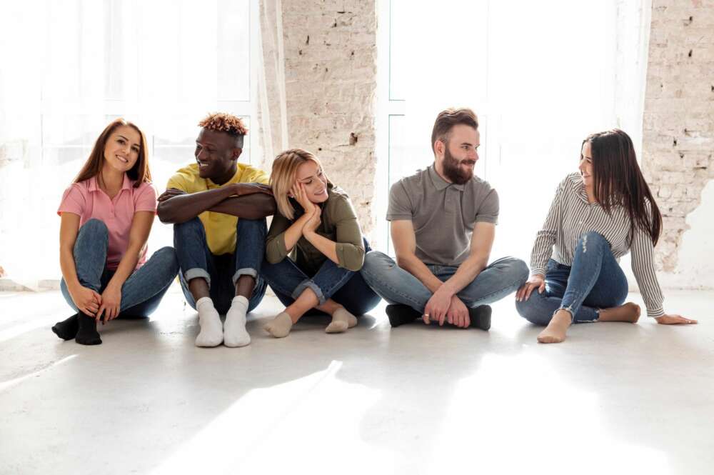 Un grupo de jóvenes conversan sentados en el suelo. Foto: Freepik.