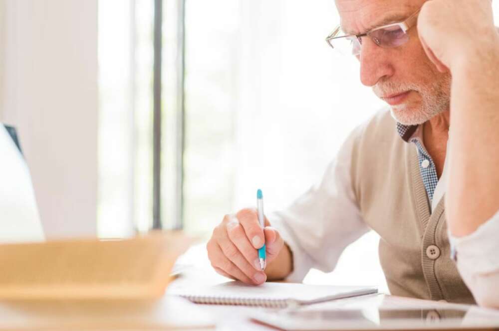 La imagen representa a un hombre leyendo el certificado de últimas voluntades de un familiar cercano fallecido.