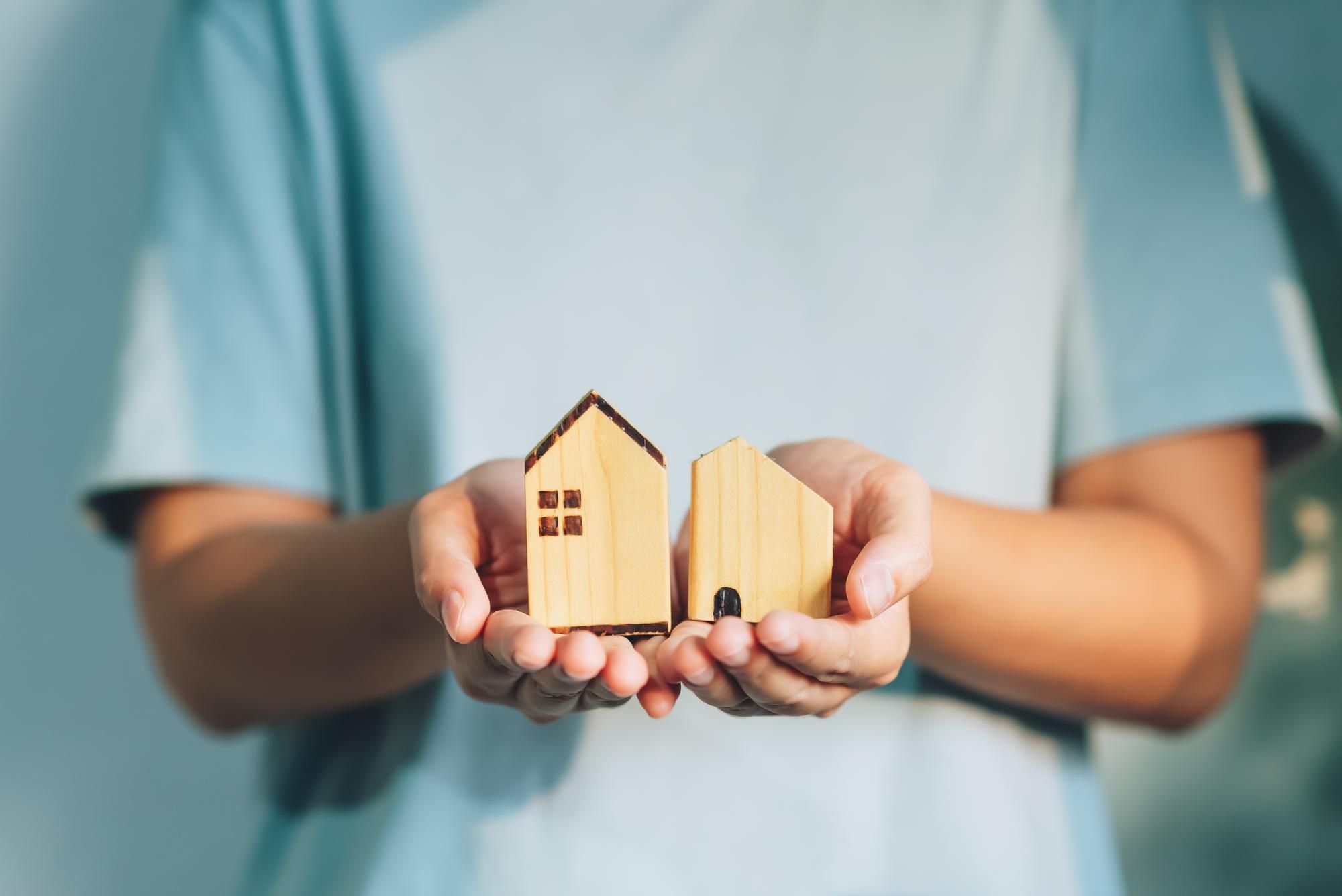 Una persona sostiene una figura de una casa de madera en sus manos. Foto: Freepik.