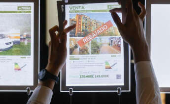 Un trabajador de una inmobiliaria coloca un cartel. Foto: EFE.