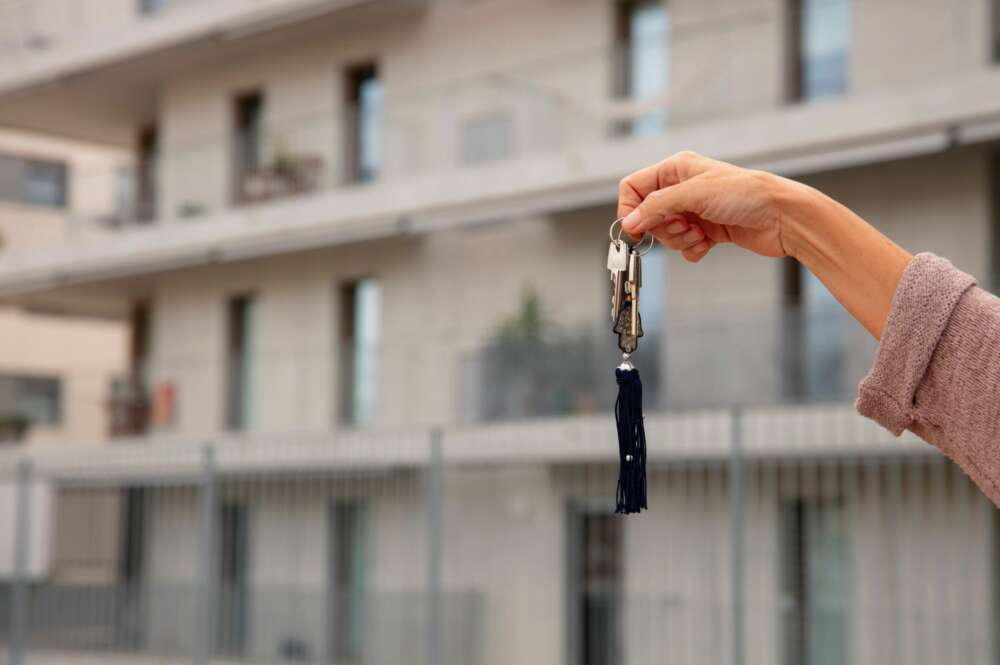 Una mano sostiene unas llaves frente a una casa. Foto: Freepik.