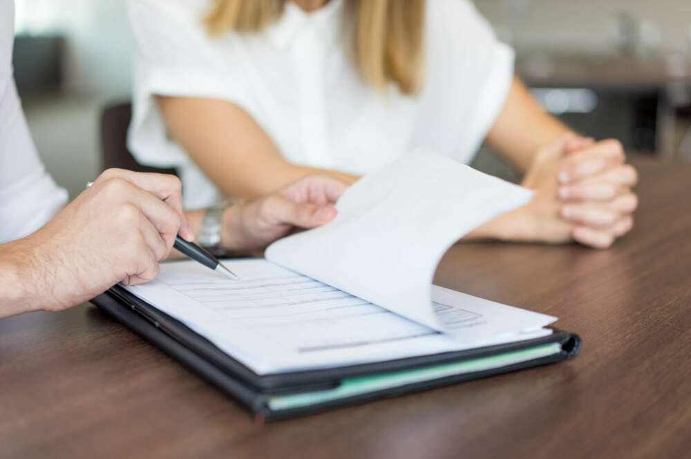 Dos personas firmando documentos en una notaria