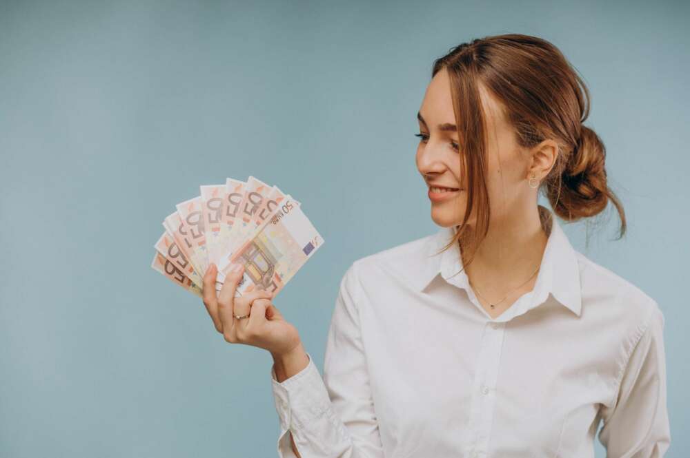 Una mujer mira distintos billetes. Préstamo. Foto: Freepik.