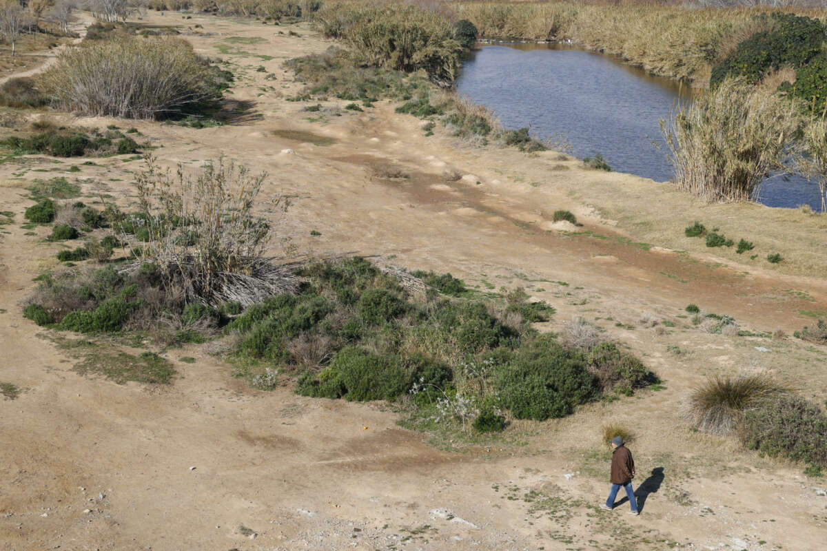 Una persona pasea por el margen urbanizado de un rio en El Prat del Llobregat. Foto: EFE/Quique García