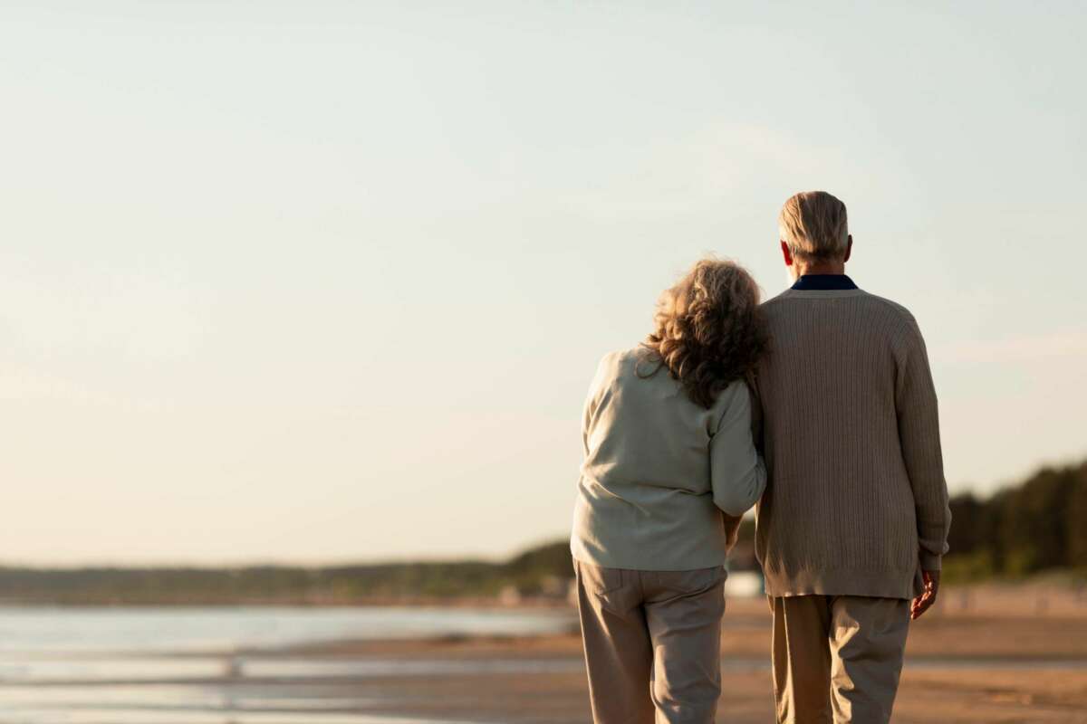 Una pareja de jubilados camina por la playa. pensión. Foto: Freepik.