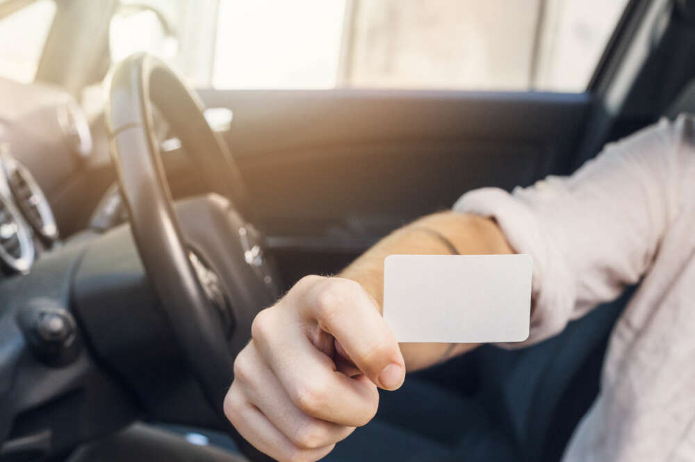 Una persona enseña su carnet de conducir.