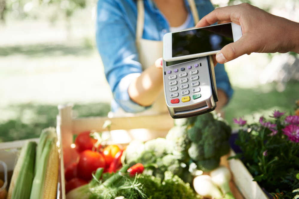 Una compra en un supermercado pagando con un datáfono y un móvil.