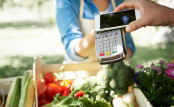 Una compra en un supermercado pagando con un datáfono y un móvil.