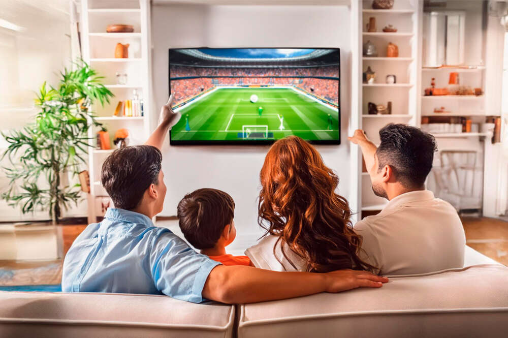 Familia viendo un partido de fútbol en el televisor de su casa